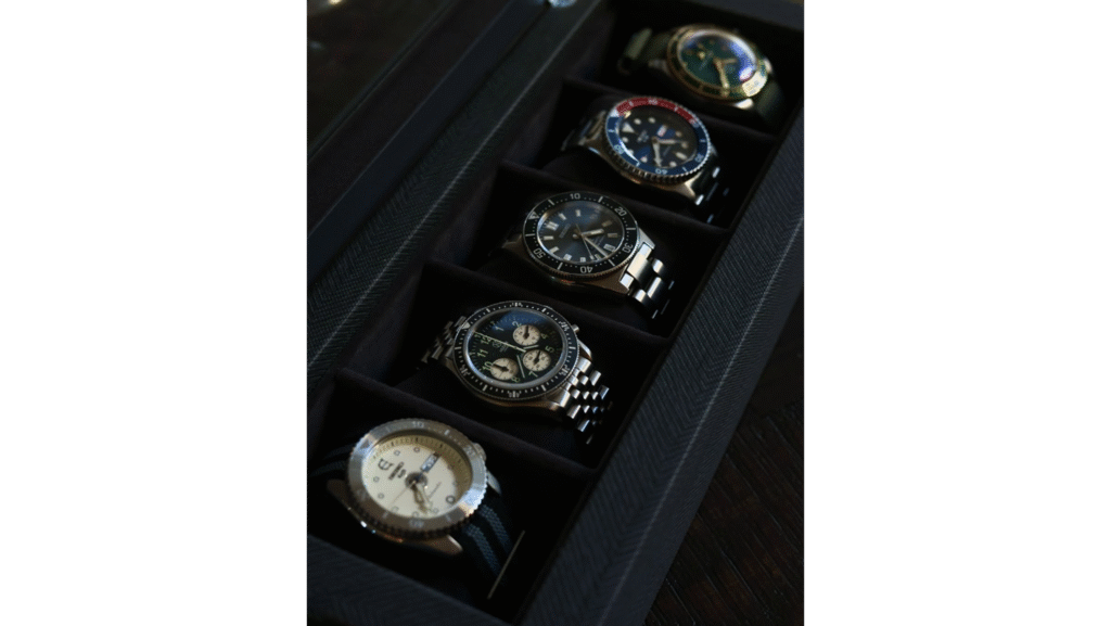 five watches displayed inside of an open watch box