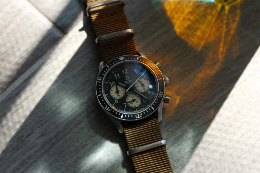 chronograph watch on a tile floor with sun and shadow hitting the watch